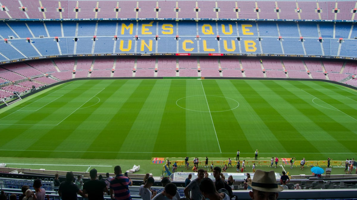 Aerial view of Camp Nou Stadium in Barcelona, showcasing the iconic 'Més Que Un Club' seating in daylight.